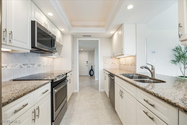 kitchen with visible vents, ornamental molding, appliances with stainless steel finishes, a raised ceiling, and a sink