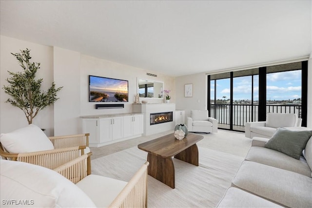 living room featuring light carpet, a glass covered fireplace, and floor to ceiling windows