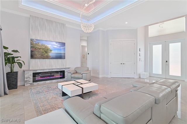 living room with baseboards, a tray ceiling, french doors, a glass covered fireplace, and crown molding