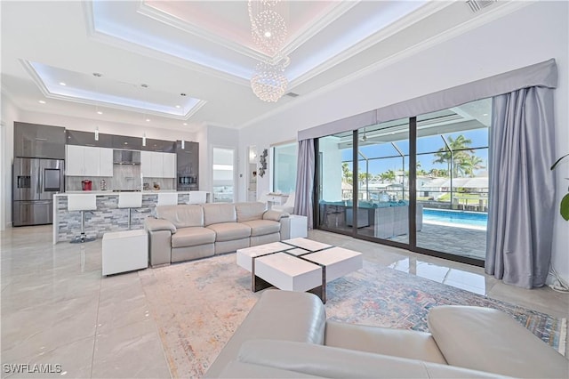 living room featuring a tray ceiling, a notable chandelier, crown molding, and marble finish floor