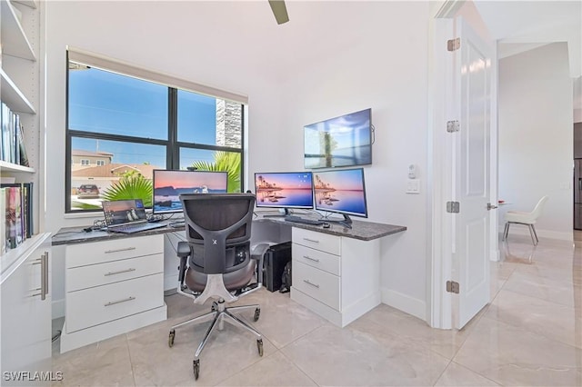 office space with a ceiling fan, baseboards, and built in study area