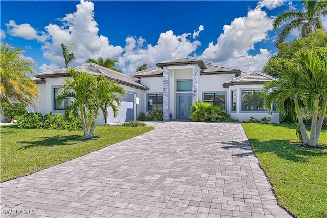 view of front facade featuring decorative driveway, a front lawn, an attached garage, and stucco siding