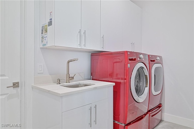 washroom with a sink, baseboards, cabinet space, and washing machine and clothes dryer