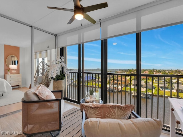 sunroom featuring a water view, plenty of natural light, and a ceiling fan