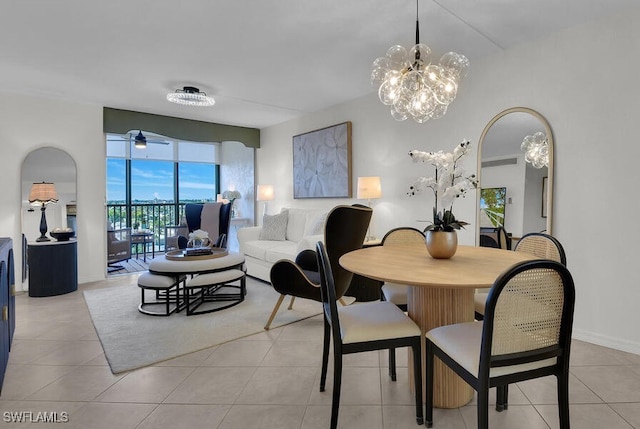 dining space with light tile patterned floors, a ceiling fan, and arched walkways