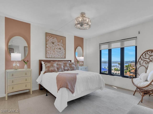 bedroom featuring a notable chandelier, baseboards, and light wood-type flooring