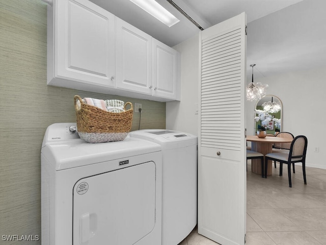 laundry area featuring light tile patterned floors, a chandelier, cabinet space, and separate washer and dryer