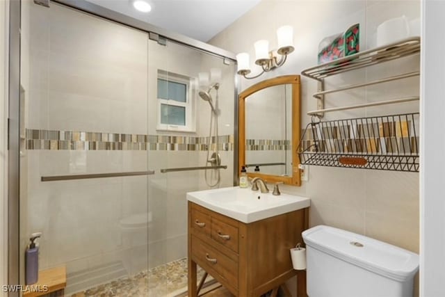 bathroom with vanity, toilet, tile walls, and a shower stall