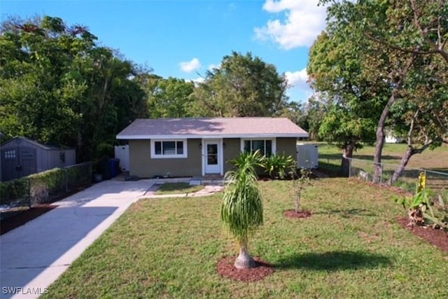 2525 4th St, Fort Myers, FL 33901 - view of front facade featuring fence, a front yard, stucco siding, an outdoor structure, and a storage unit
