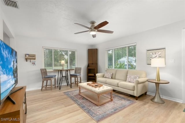 living room featuring a wealth of natural light, visible vents, and light wood-type flooring