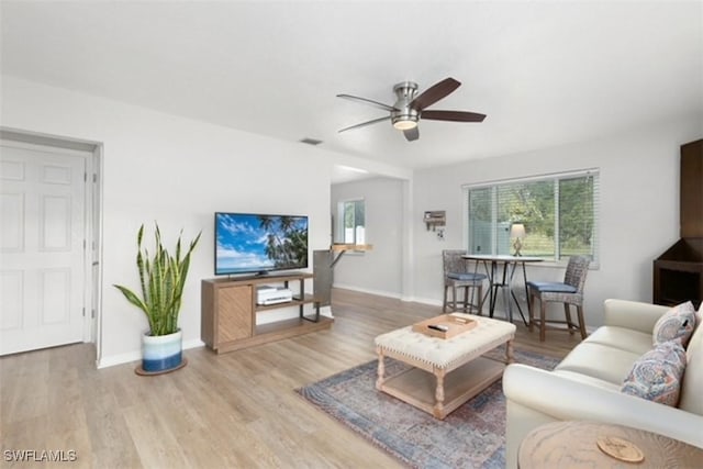 living room with ceiling fan, visible vents, baseboards, and wood finished floors