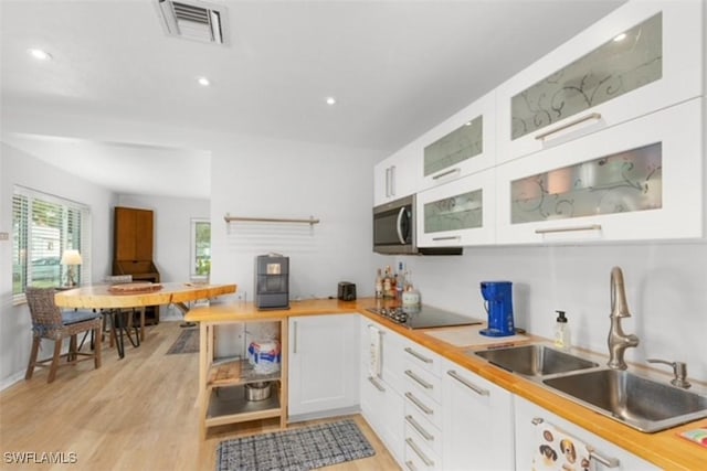 kitchen with visible vents, a sink, light wood-style floors, white cabinets, and black electric cooktop