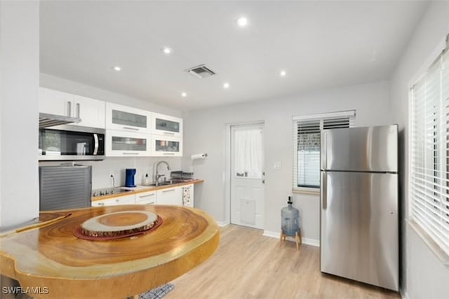 kitchen featuring plenty of natural light, white cabinets, stainless steel appliances, and light wood-style flooring