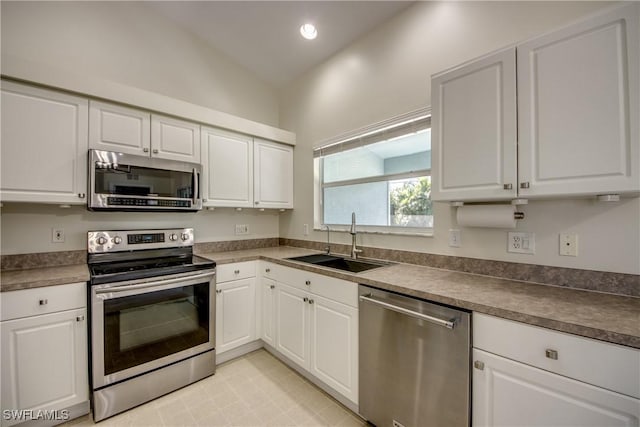 kitchen featuring a sink, stainless steel appliances, dark countertops, and white cabinetry