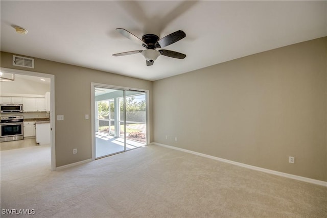 empty room featuring visible vents, light carpet, baseboards, and a ceiling fan