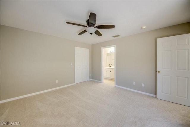 unfurnished bedroom with a ceiling fan, visible vents, baseboards, ensuite bathroom, and light colored carpet