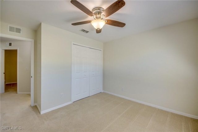 unfurnished bedroom featuring light colored carpet, visible vents, a closet, and baseboards