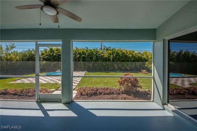 unfurnished sunroom with ceiling fan