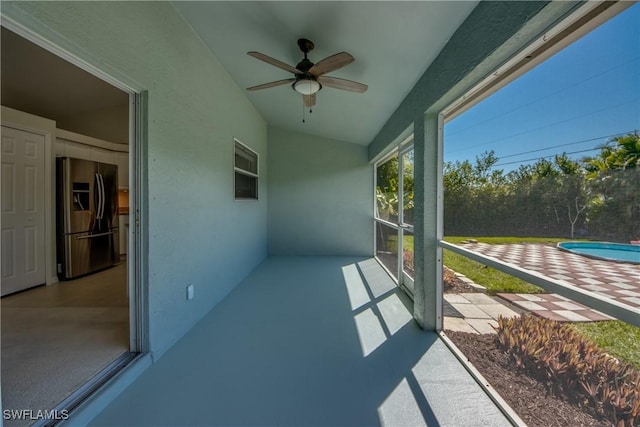 unfurnished sunroom with a ceiling fan and vaulted ceiling