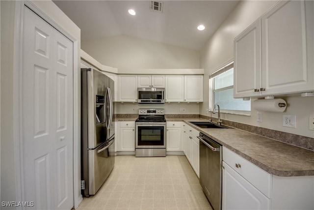 kitchen featuring visible vents, a sink, stainless steel appliances, vaulted ceiling, and white cabinets