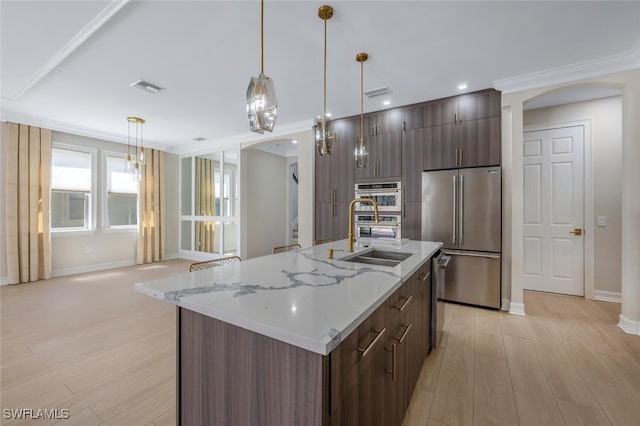 kitchen featuring visible vents, arched walkways, a sink, appliances with stainless steel finishes, and modern cabinets