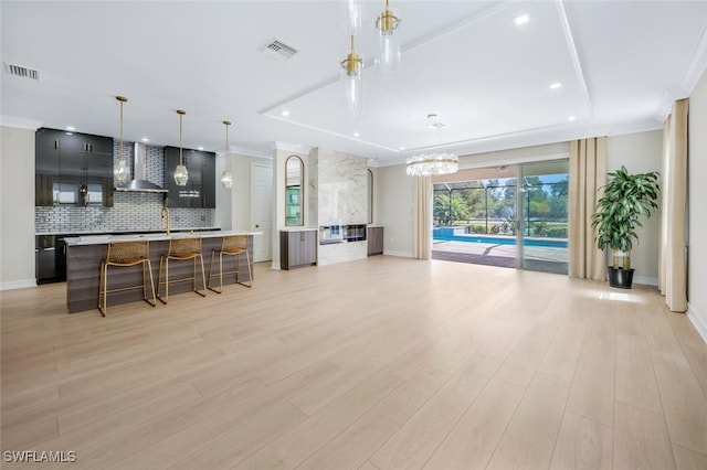 kitchen with visible vents, light countertops, ornamental molding, decorative backsplash, and wall chimney exhaust hood