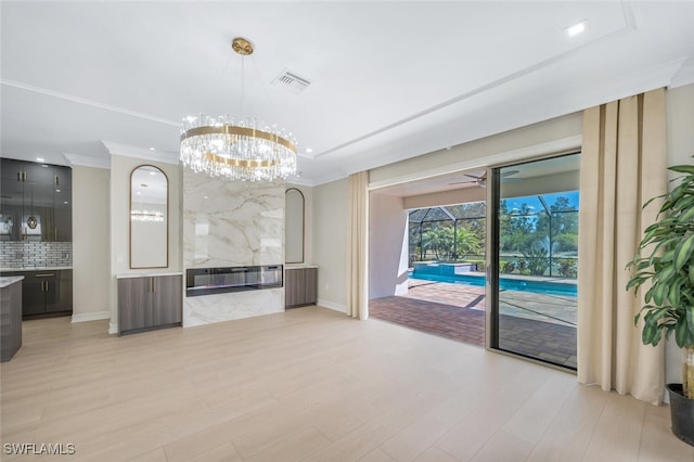 unfurnished living room featuring visible vents, light wood finished floors, an inviting chandelier, radiator heating unit, and ornamental molding