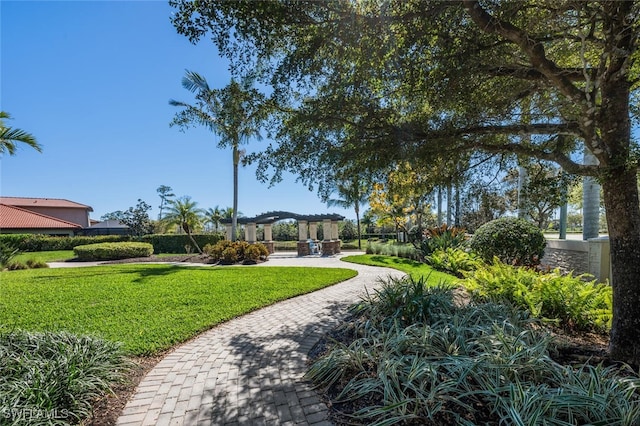 view of property's community with a yard and a pergola