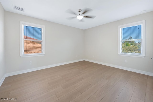 empty room with light wood-type flooring, visible vents, baseboards, and ceiling fan