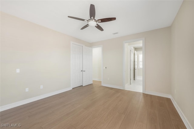 empty room featuring light wood-style flooring, baseboards, visible vents, and ceiling fan