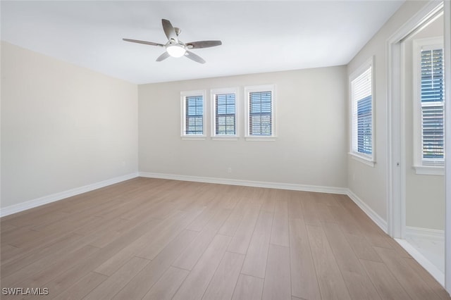 unfurnished room with a wealth of natural light, light wood-style floors, and a ceiling fan