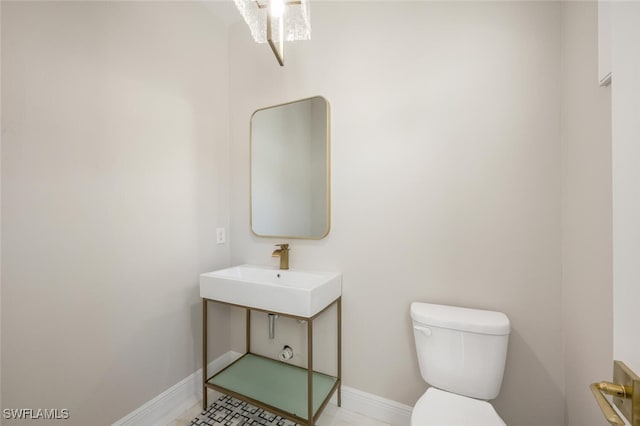 half bath with a sink, baseboards, and toilet
