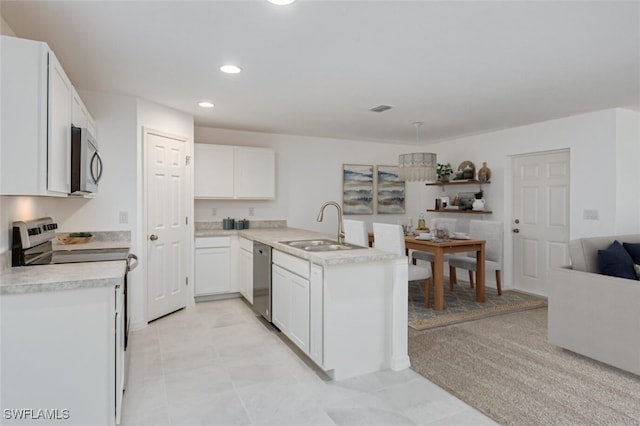 kitchen with a sink, open floor plan, white cabinetry, appliances with stainless steel finishes, and light countertops