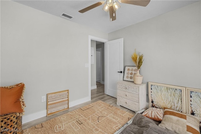 bedroom with visible vents, baseboards, wood finished floors, and a ceiling fan