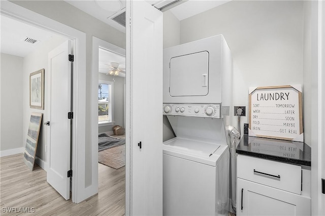 washroom with light wood-type flooring, visible vents, stacked washer and dryer, and laundry area