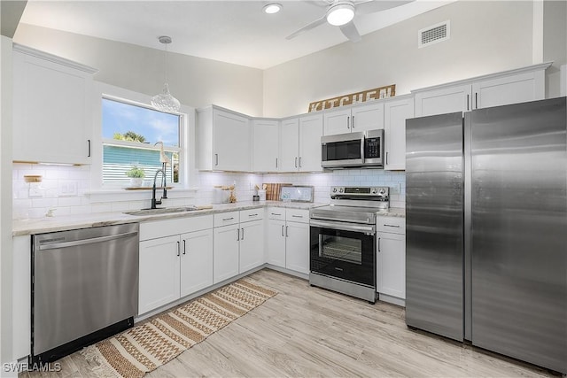 kitchen featuring visible vents, light wood-style flooring, a sink, stainless steel appliances, and tasteful backsplash