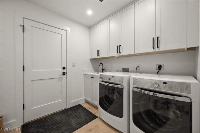 washroom with a sink, recessed lighting, cabinet space, separate washer and dryer, and light wood finished floors