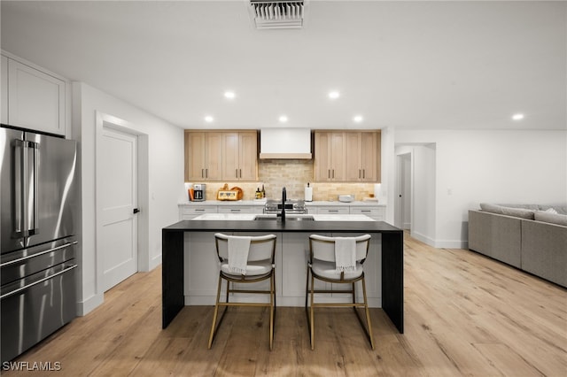 kitchen with decorative backsplash, visible vents, high quality fridge, and premium range hood