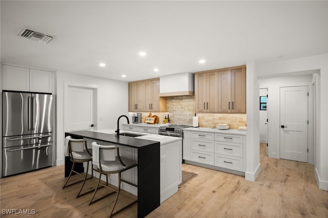 kitchen with visible vents, light wood-type flooring, custom range hood, a sink, and appliances with stainless steel finishes