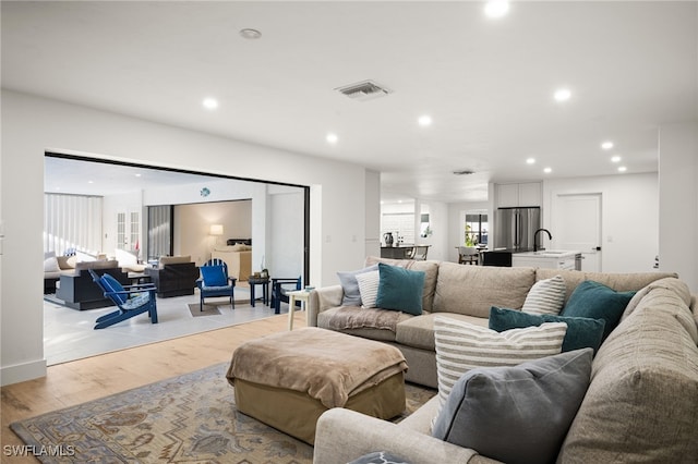 living room featuring recessed lighting, visible vents, and light wood-type flooring