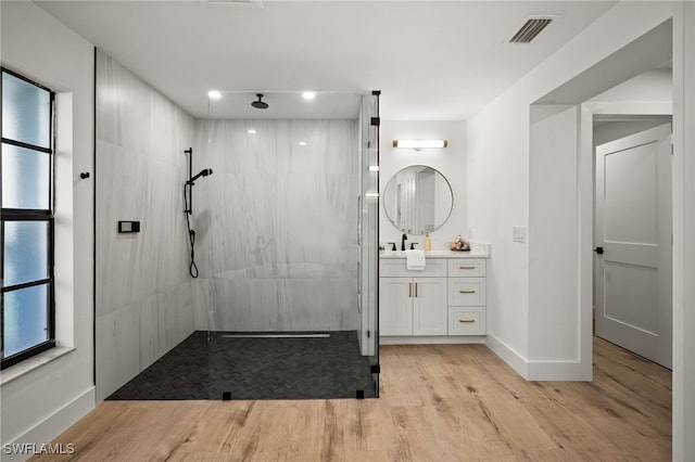 bathroom with visible vents, a walk in shower, baseboards, wood finished floors, and vanity