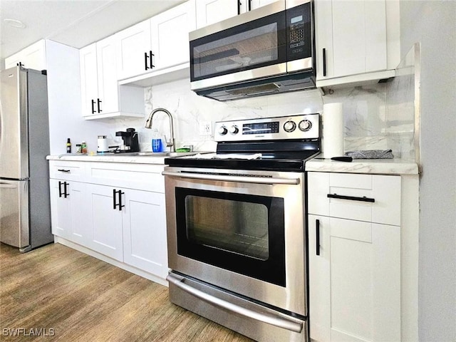 5529/5531 10th Ave, Fort Myers, FL 33907 - kitchen with appliances with stainless steel finishes, light wood finished floors, tasteful backsplash, and light countertops