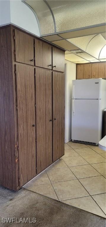 kitchen with light tile patterned floors and freestanding refrigerator