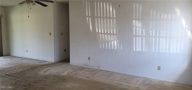 carpeted empty room featuring baseboards and a ceiling fan