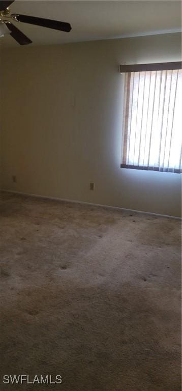 unfurnished room featuring a ceiling fan, dark colored carpet, and baseboards