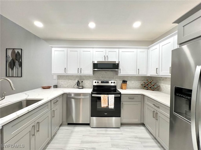 kitchen featuring a sink, light stone countertops, appliances with stainless steel finishes, and gray cabinetry