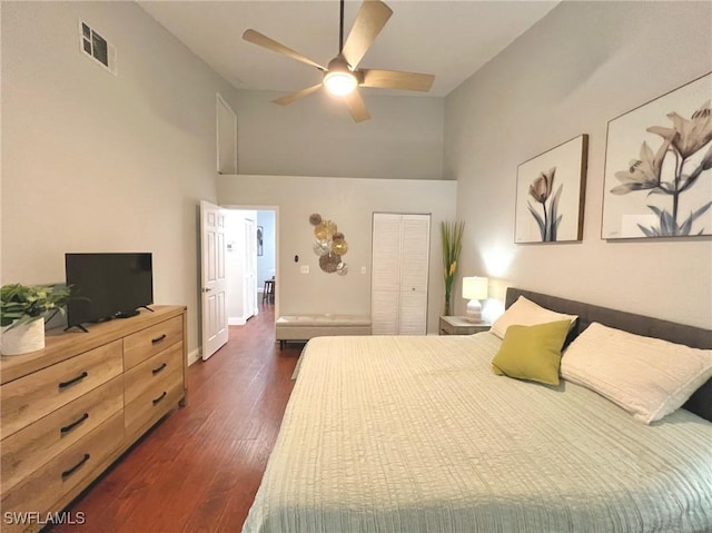 bedroom with visible vents, a closet, dark wood-style floors, and a towering ceiling