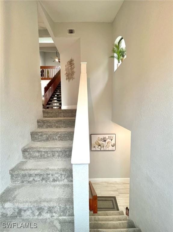 staircase with visible vents, baseboards, wood finished floors, and a ceiling fan