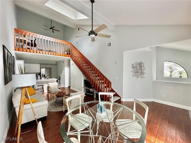 dining space featuring ceiling fan, visible vents, high vaulted ceiling, stairs, and hardwood / wood-style floors