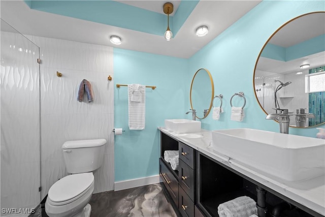 bathroom with double vanity, toilet, baseboards, and a sink